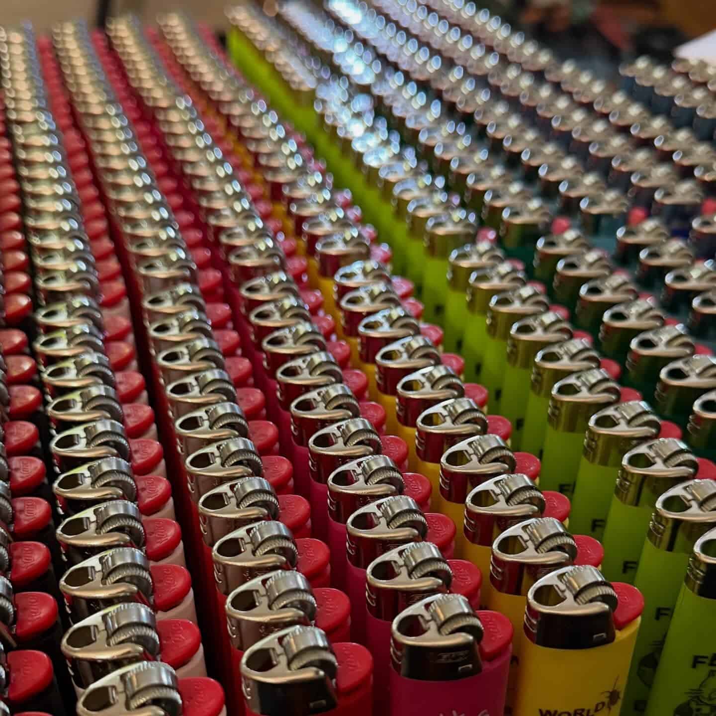 Large batch of colorful custom lighters arranged in closely packed rows
